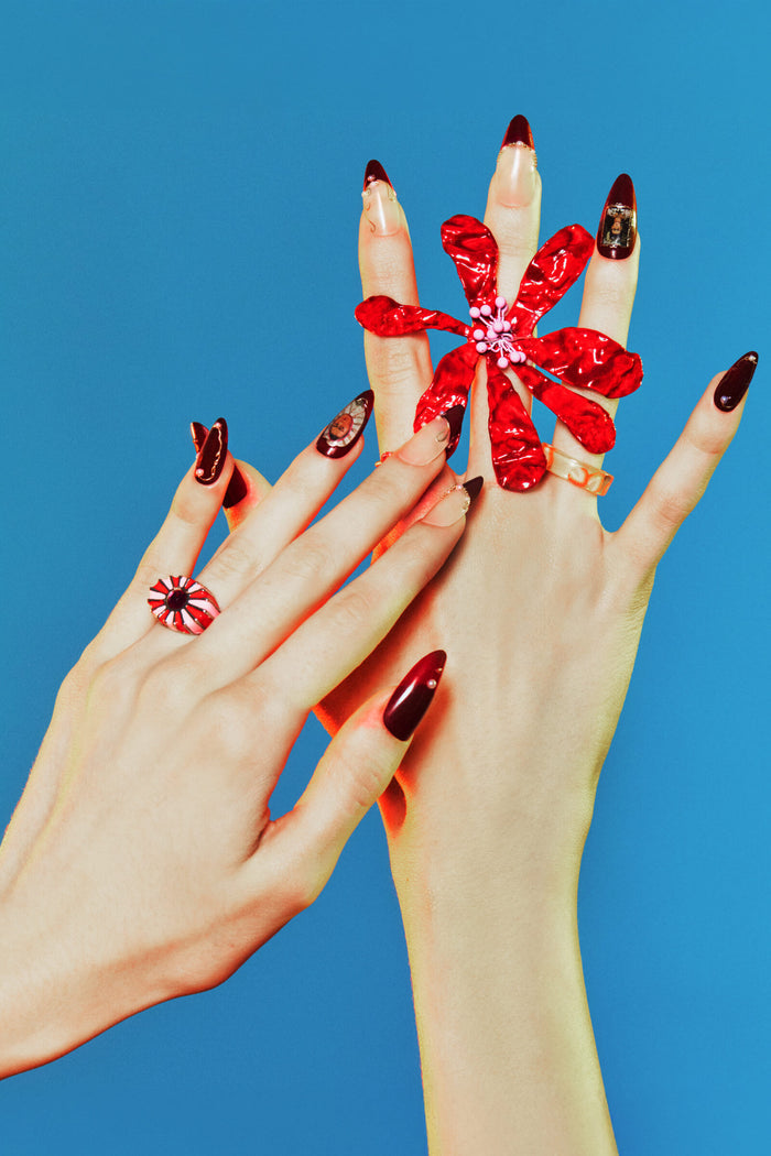 Almond press-on nails with a Frida Kahlo-inspired design, featuring dark red tips and a small portrait on one nail.