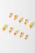 Assortment of cream-colored press-on nails with fruit designs including strawberries, kiwis, oranges, and pineapple slices.