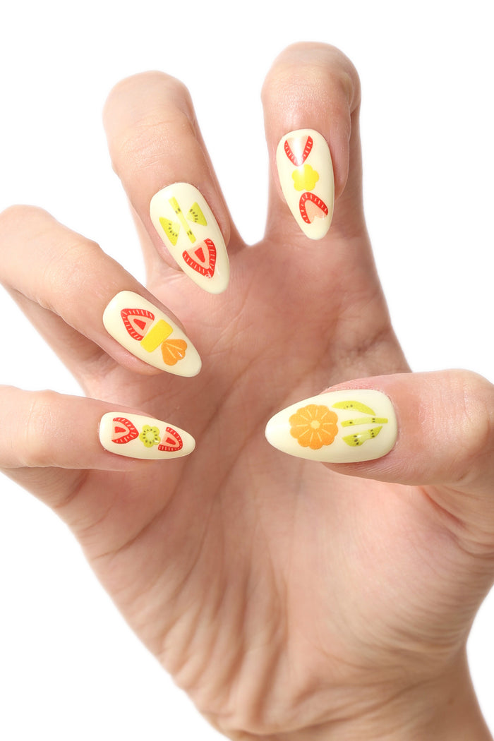 Cream press-on nails with cute fruit designs including strawberries, kiwis, and oranges.