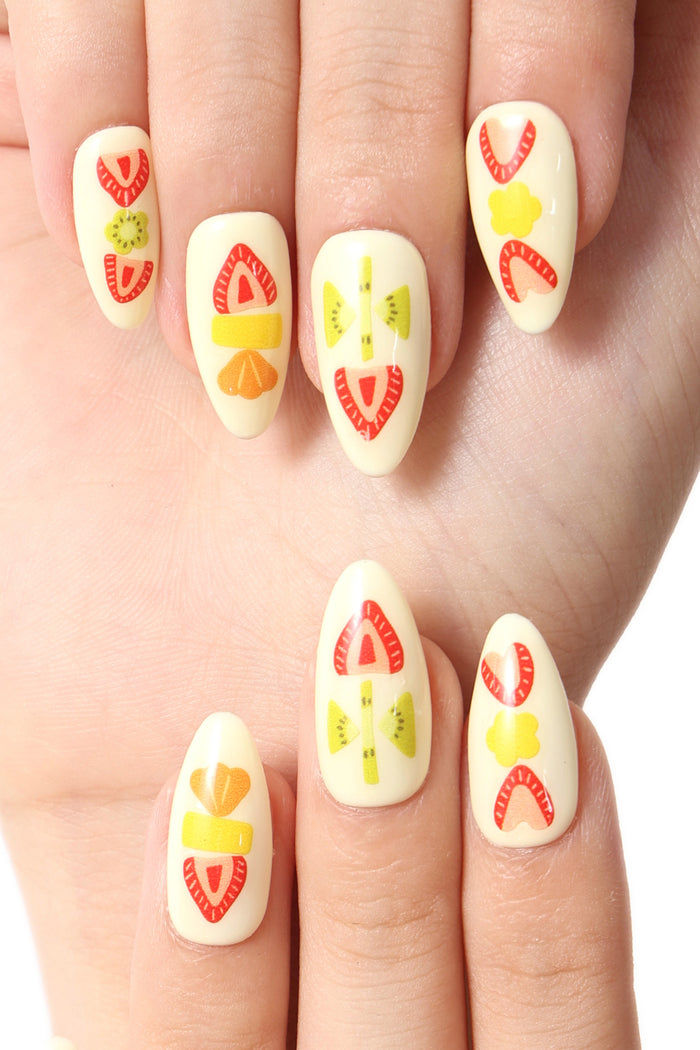 Press-on nails with a cream base, featuring cute fruit designs like strawberries, kiwis, and oranges.