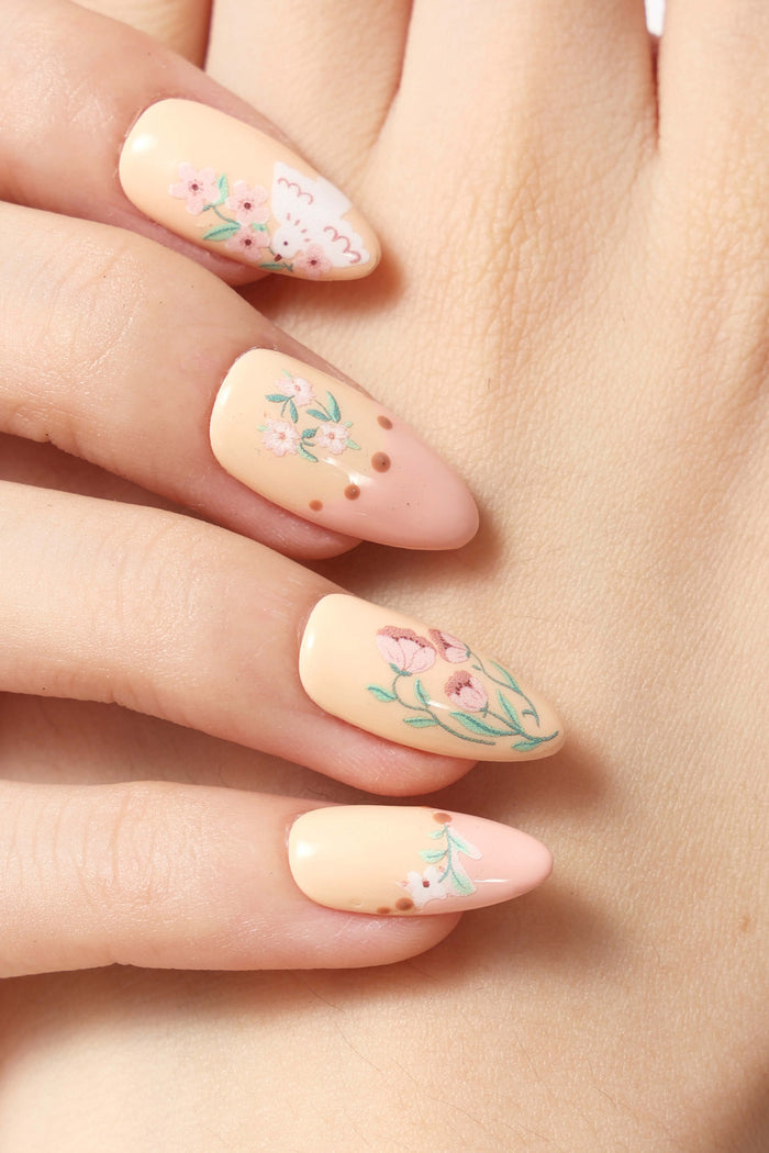 Elaine Lee's Garden Melody press-on nails feature soft peach and pink colors with delicate floral and dove designs.