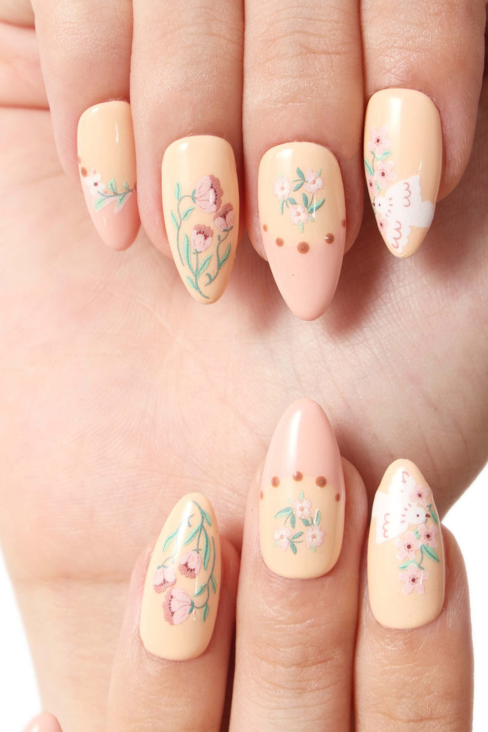 Garden Melody press-on nails with floral and dove designs on a soft peach base.