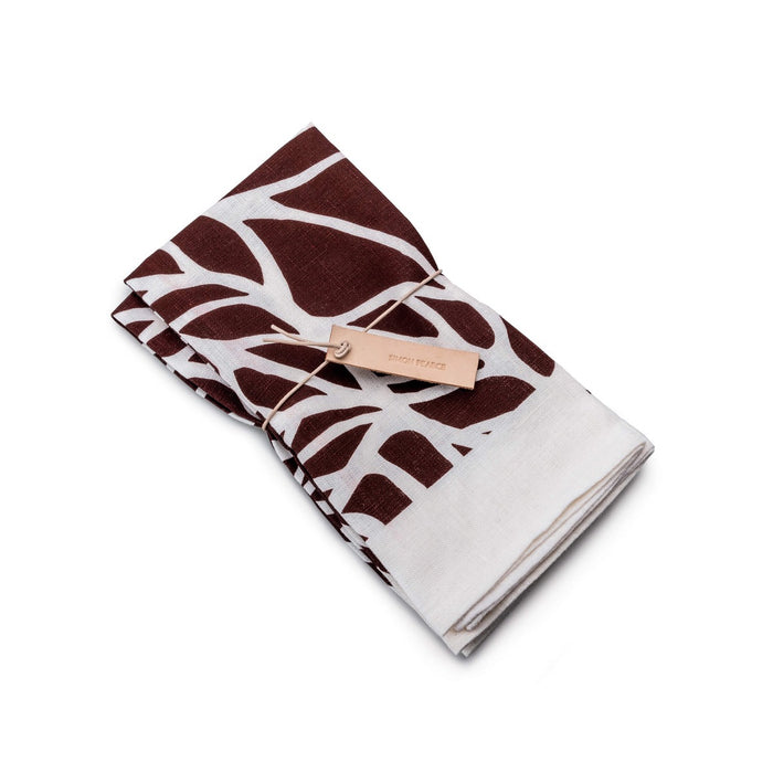 Two folded napkins with garnet and white leaf block print pattern, tied with a tan fabric band.