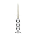 Clear glass candlestick with three stacked spheres, metal candle holder ring, and cream taper candle.
