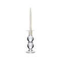 Clear glass candlestick with stacked spherical base holding a cream-colored taper candle.