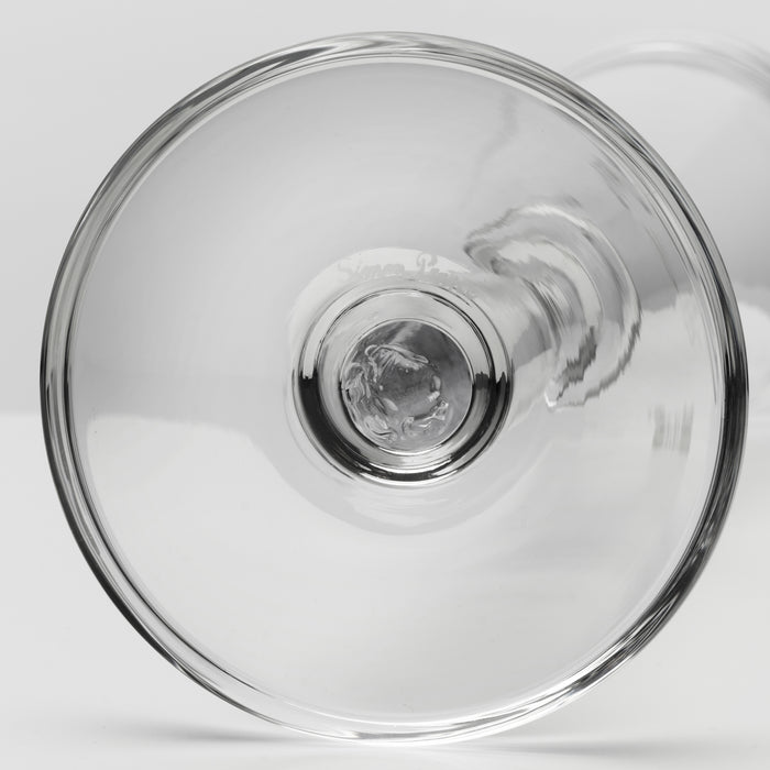 A close-up studio shot of a clear glass product, shown from above against a light gray background.