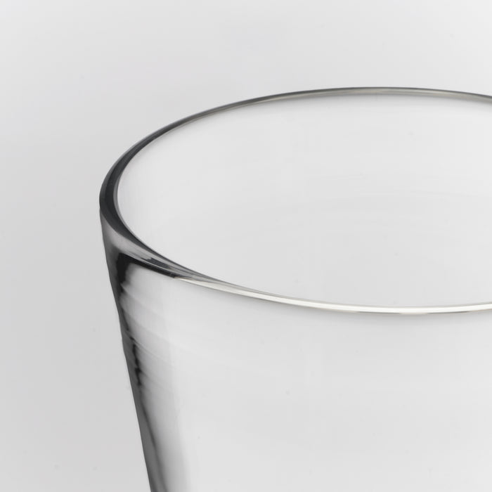 Close-up of a clear glass tumbler showing the rim and part of the body against a light gray background.