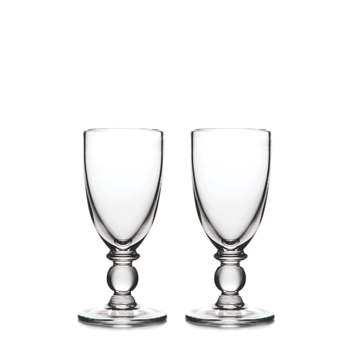 Two clear glass wine goblets with bulbous stems and round bases positioned side by side.