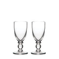 Two clear glass wine goblets with bulbous stems and round bases positioned side by side.