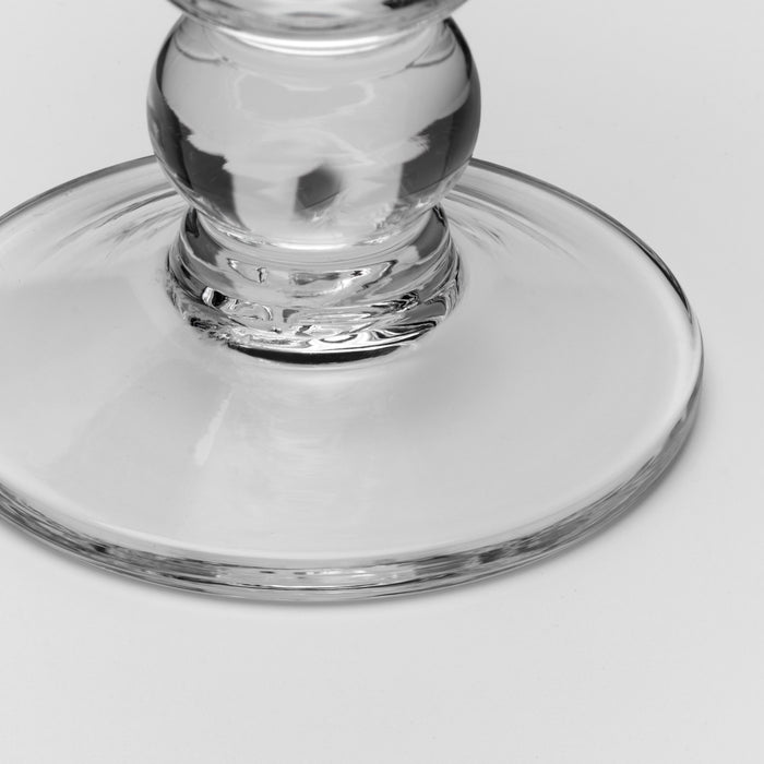 Close-up of a clear glass base and stem on a light gray background.