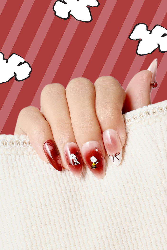 Almond press-on nails featuring Snoopy characters and heart designs in red and white gradient.