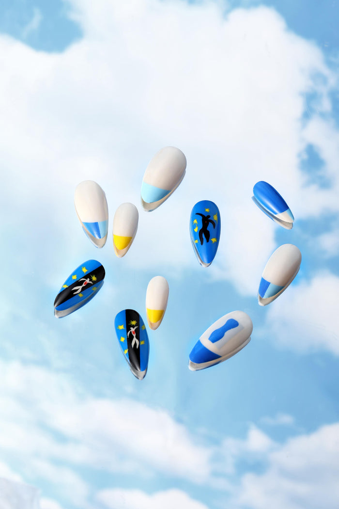 Almond press-on nails with Henri Matisse Icarus art and abstract blue & yellow designs against a sky background.