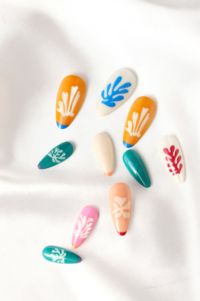 Almond press-on nails with Matisse-inspired floral cut-out designs in orange, white, teal, pink, and peach.