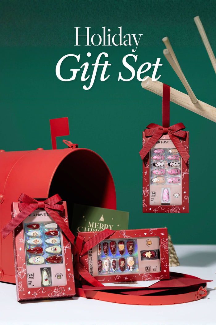 Holiday Gift Set with festive press-on nails in red boxes tied with ribbon. Designs include dogs, teddy bears, and floral patterns.