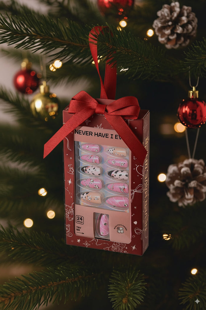 Dashing Dalmation almond press-on nails gift box with dalmatian spots and pink accents, hanging on a Christmas tree.