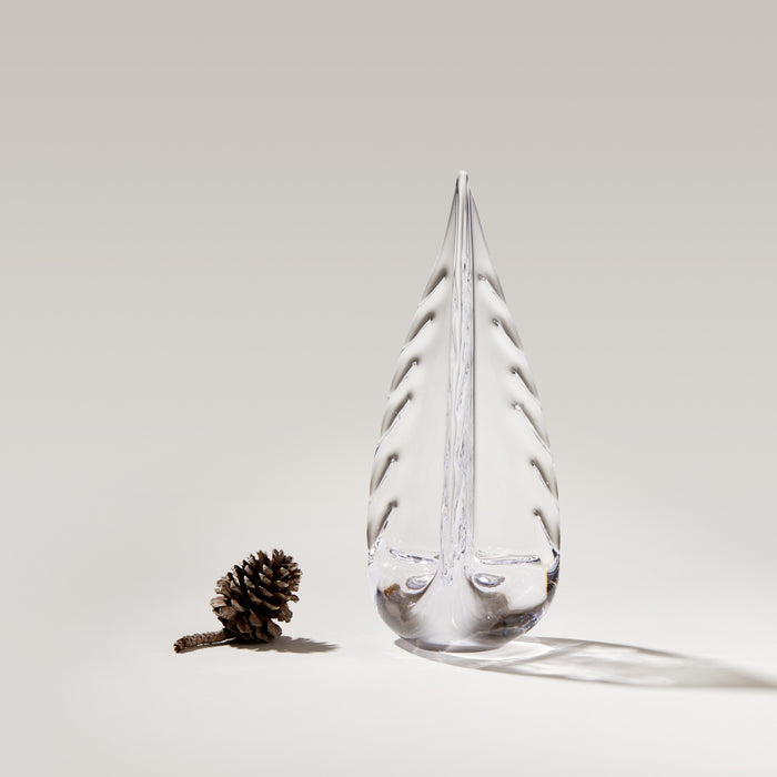 Clear glass teardrop-shaped vessel with frost-like coating and evergreen branch design, displayed next to a pinecone.