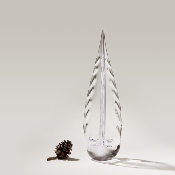 Clear teardrop-shaped glass ornament with frosted evergreen tree design and pinecone beside it.