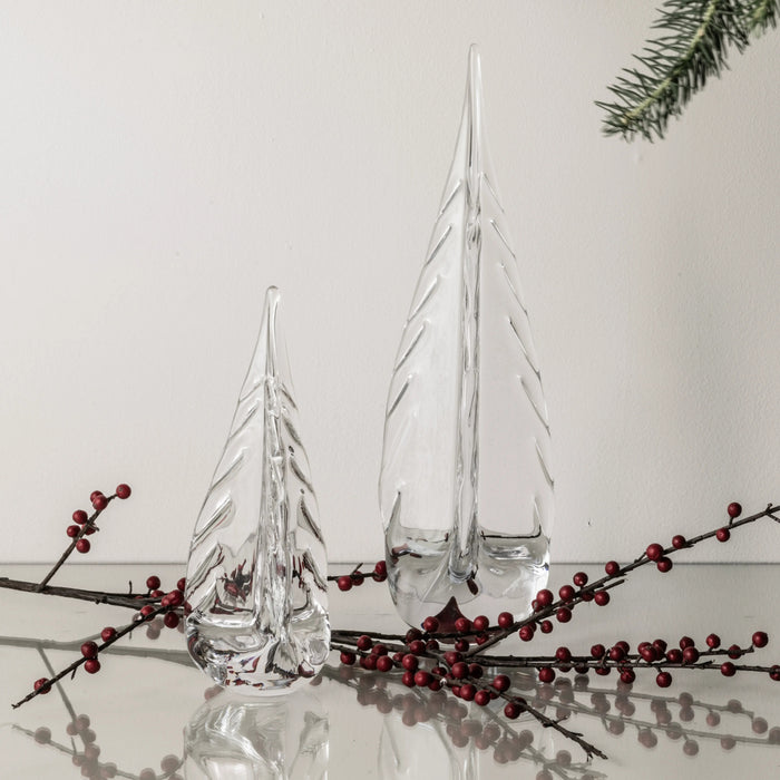 Clear glass tree-shaped decorations with textured surfaces, displayed with red berries and evergreen sprigs.