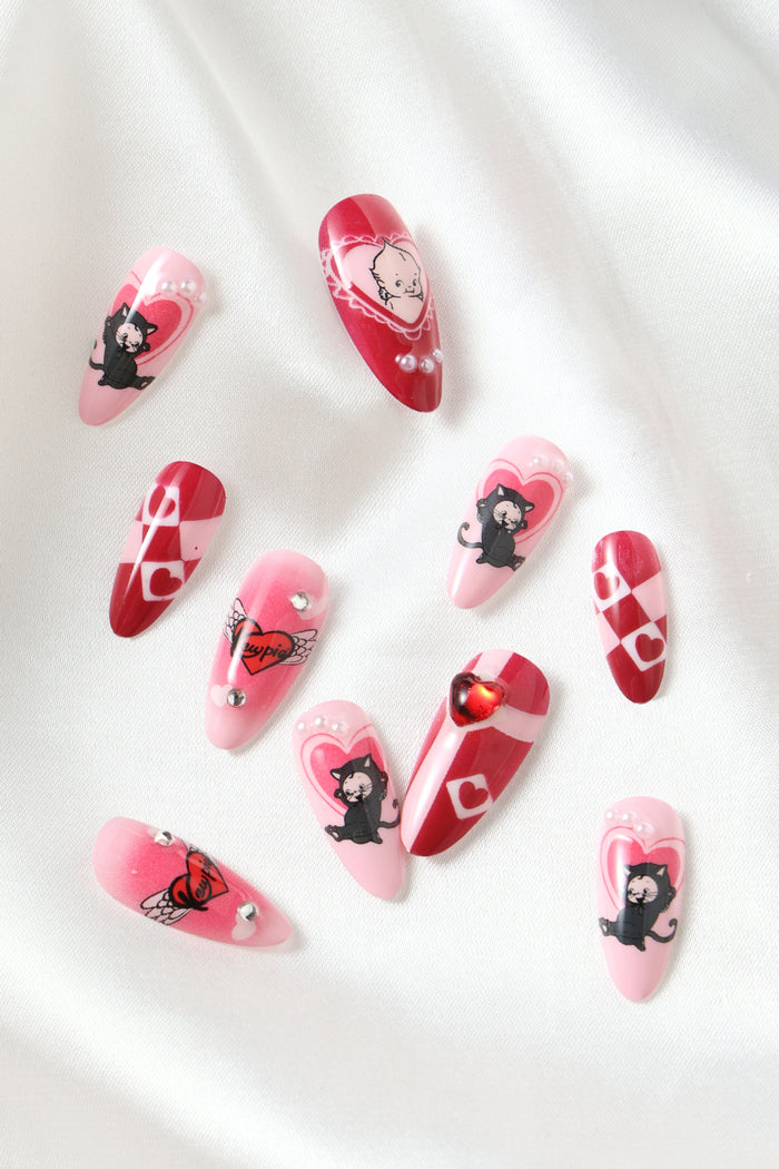 Cute pink and red press-on nails featuring black cats, hearts, and pearls.