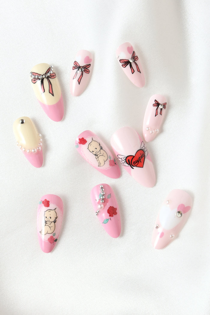 Kewpie Pastel press-on nails with baby, rose, and heart designs. Pastel pink and cream.