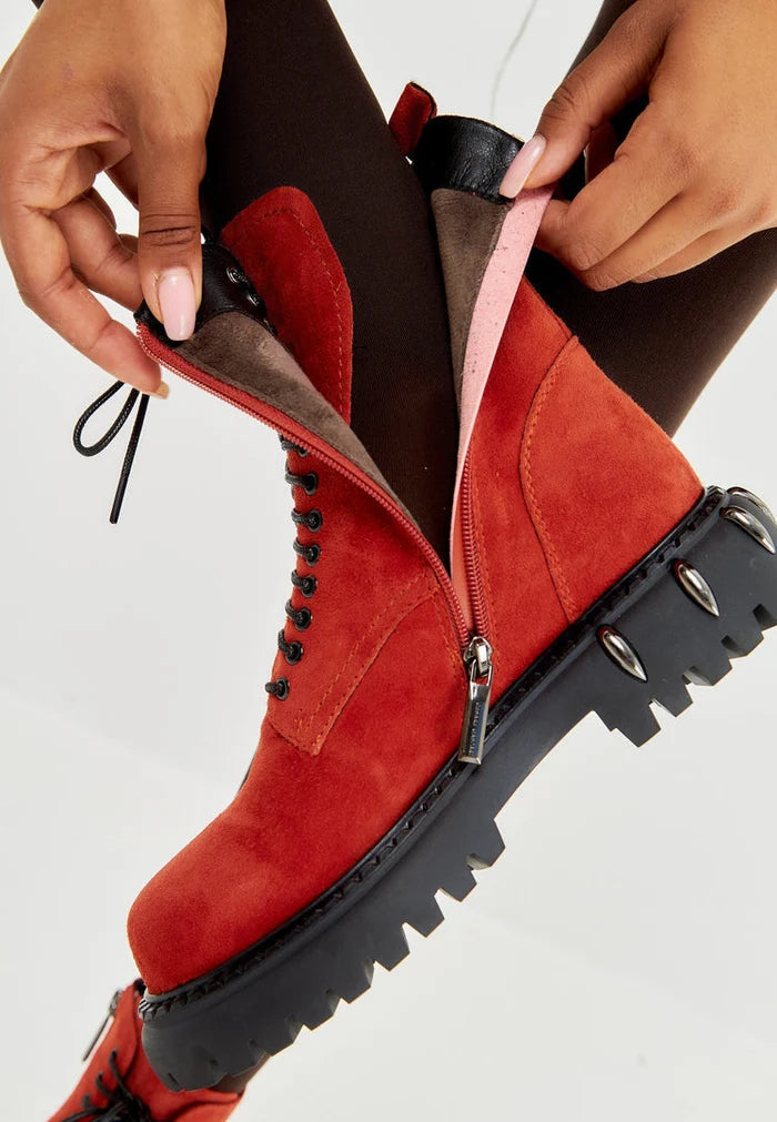 A pair of stylish red lace-up combat boots for women with a chunky sole, perfect for rocking the latest fashion trends.