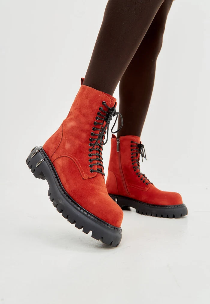 A stylish pair of red lace-up combat boots with chunky soles, perfect for any fashion-forward woman looking to make a statement with her footwear.