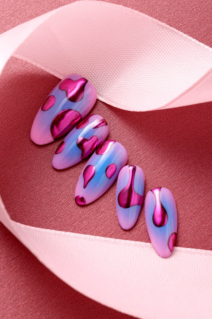 Press-on nails with a pink and blue gradient background and metallic pink lava lamp-like shapes.