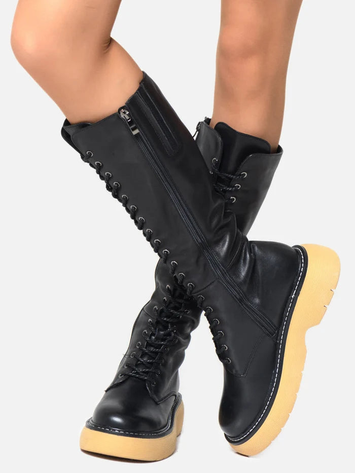 A close-up of a sleek pair of black leather knee-high lace-up boots.