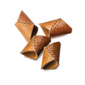 Four brown leather napkin rings with cream stitching detail arranged in a circle.