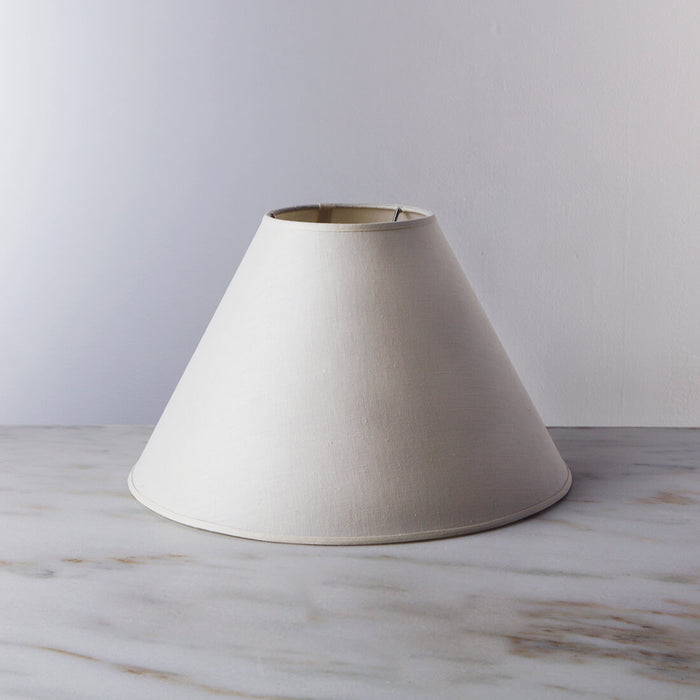 Cream-colored linen empire lamp shade with tapered cone shape and metal top rim.