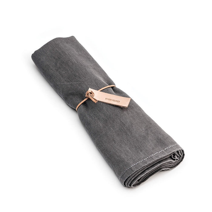 Grey linen table runner rolled and tied with a rose gold band.