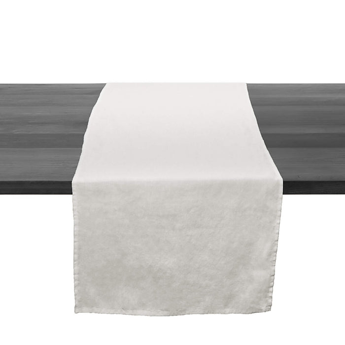 White linen table runner with raw edges draped across a dark wooden table surface.