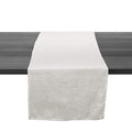 White linen table runner with raw edges draped across a dark wooden table surface.