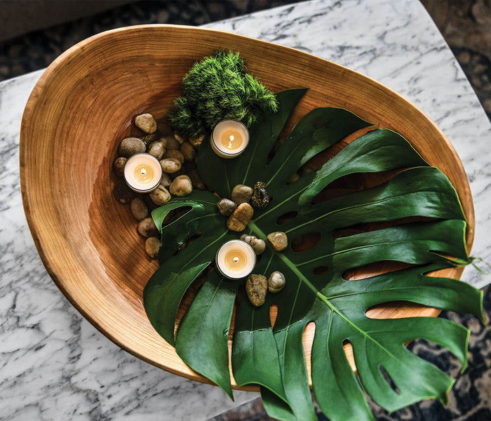 Cherry wood bowl with natural live edge, displayed with decorative moss, candles, stones, and green foliage.
