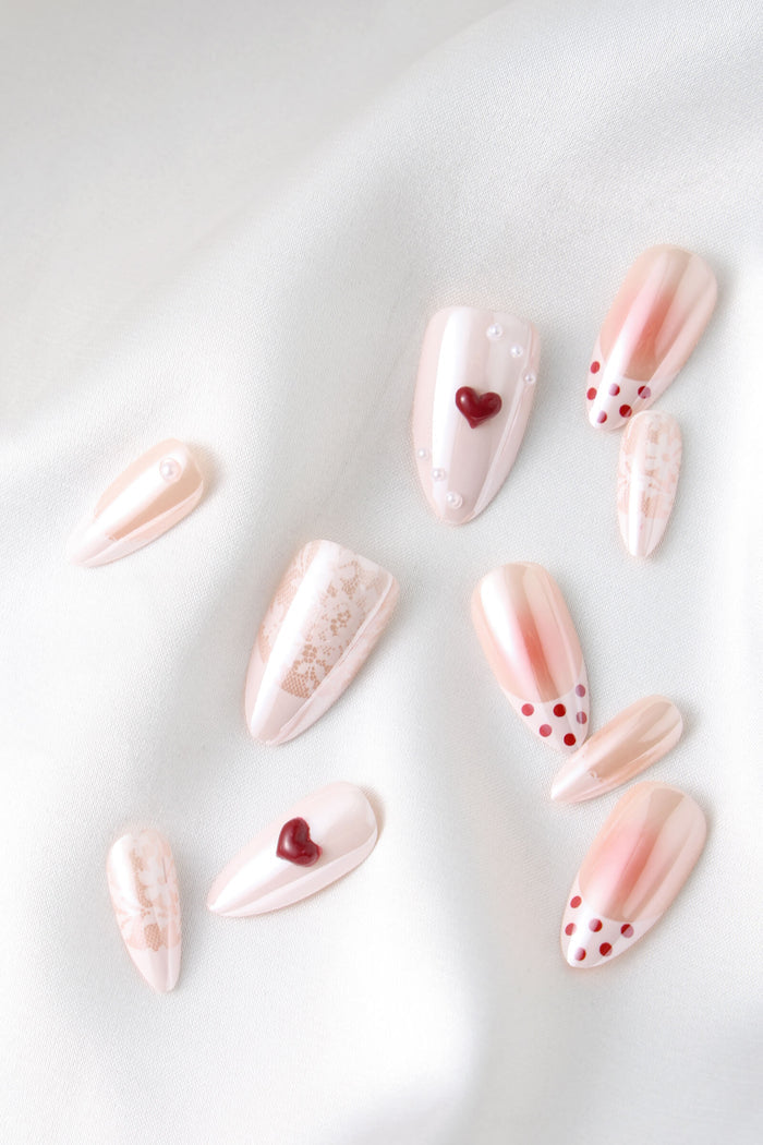 LOVER GIRL almond press-on nails with pearl and heart details, and red polka dots.