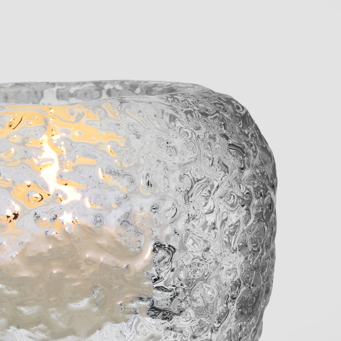 White textured tealight holder with lit yellow flame visible through cutout opening.