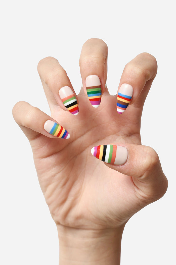 Press-on nails with a nude base featuring colorful striped designs in red, orange, yellow, green, blue, brown, and purple.