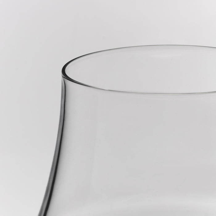 Clear glass wine glass with curved bowl and thin rim against neutral background.