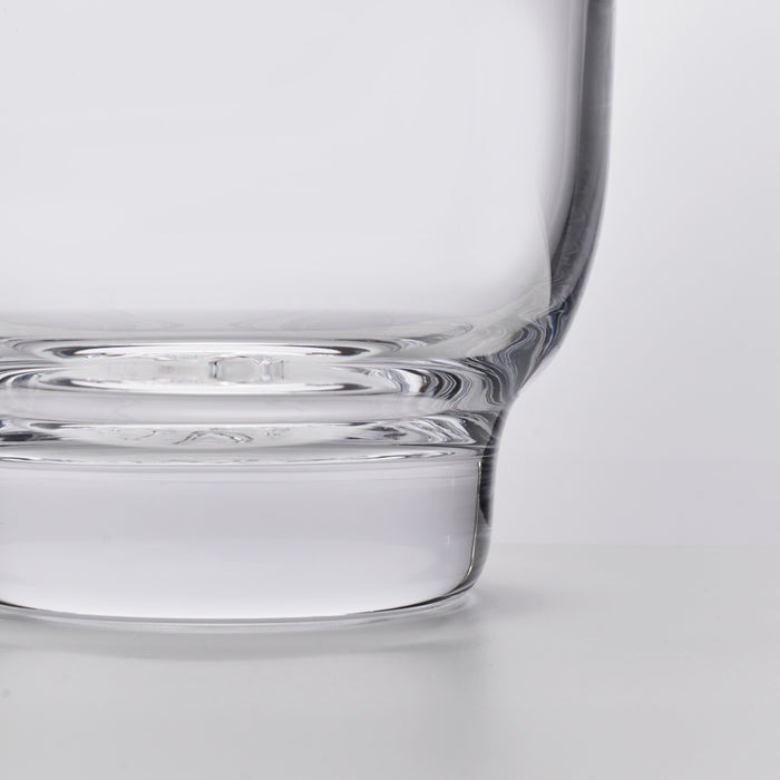Clear glass ice bucket with cylindrical body and wide flat base, shown from side angle.