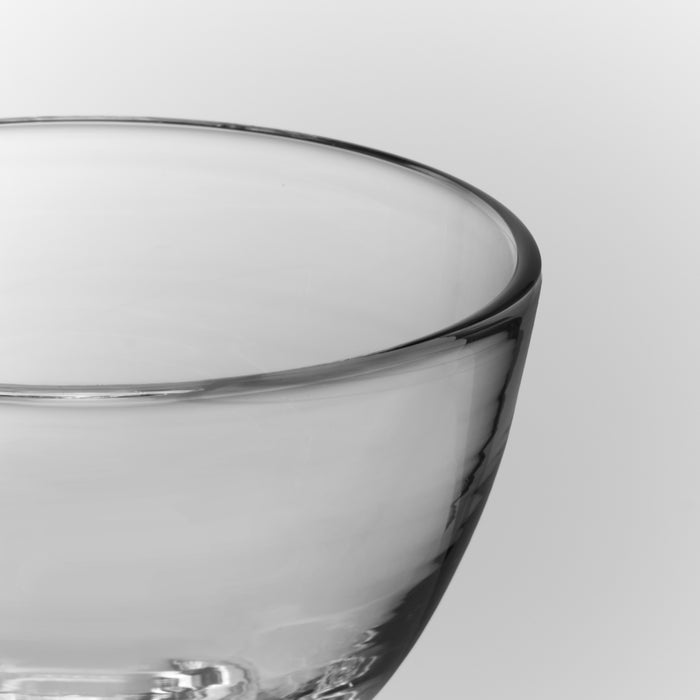 Close-up of a clear glass martini glass with curved rim and bowl shape against a white background.