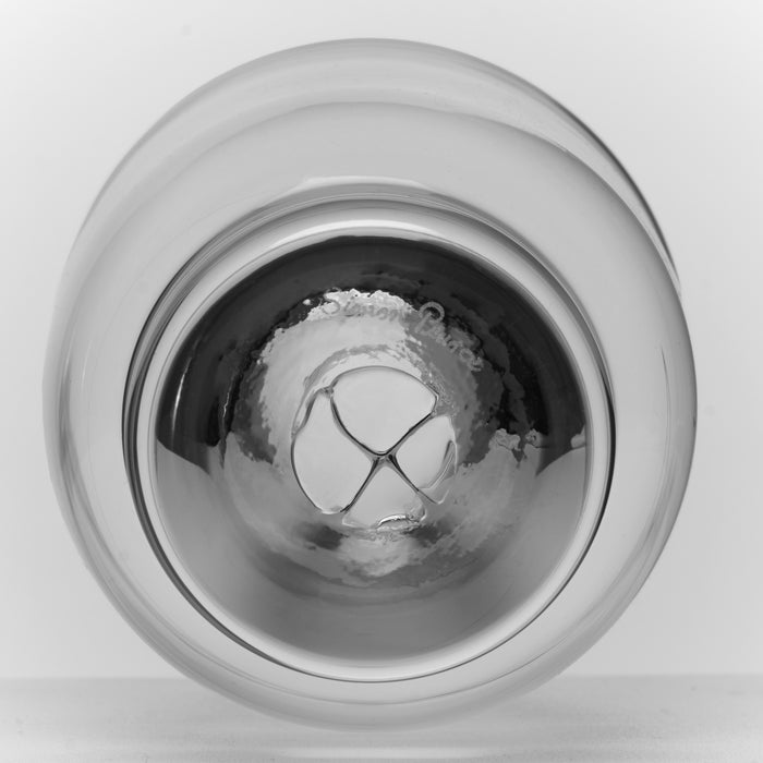 Clear glass tumbler with ice cubes inside, shown from above against white background.