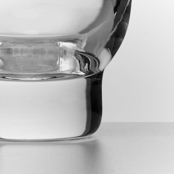 Clear glass tumbler with black handle, shown in close-up detail against white background.