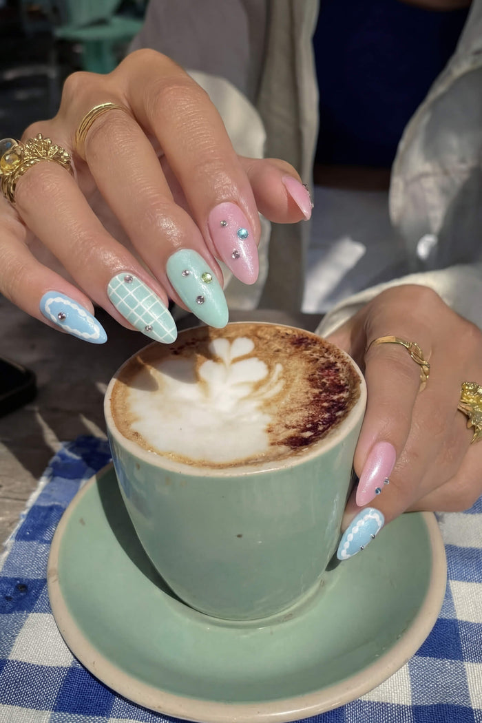 Pastel almond press-on nails with Miffy-inspired designs, holding latte.