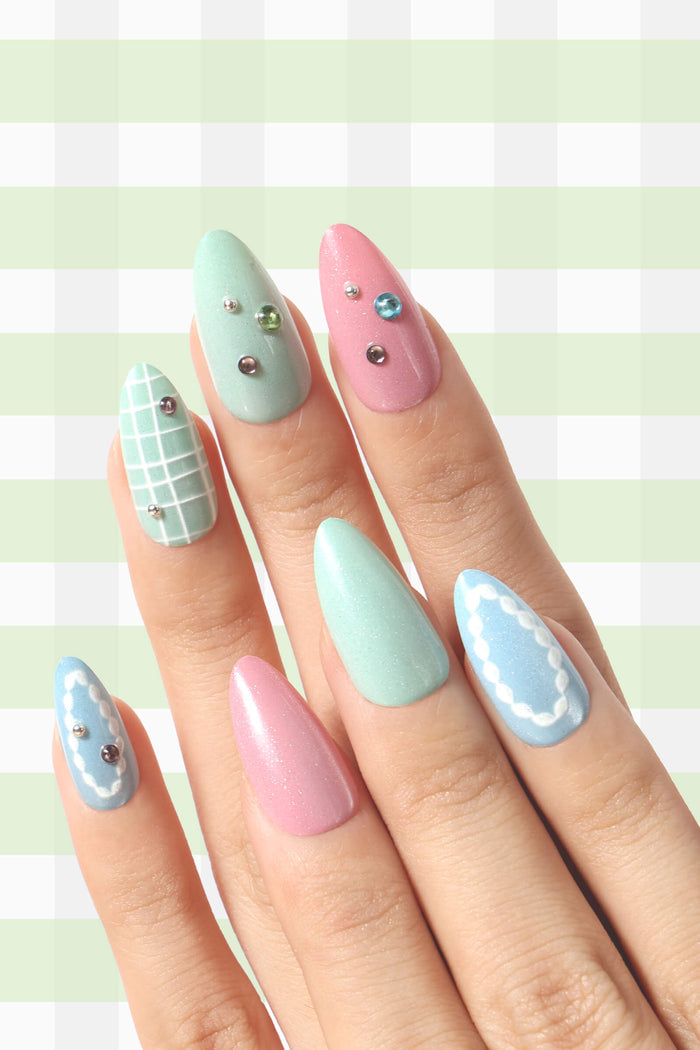 Almond press-on nails in pastel pink, mint green, and baby blue with charming designs like a grid, pearls, and gems.