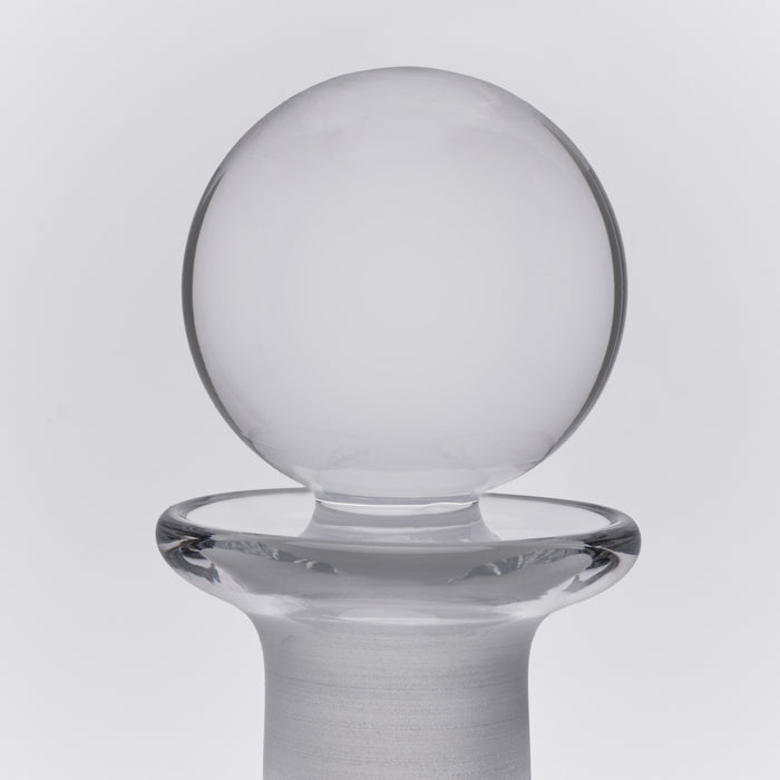 Clear glass decanter with spherical bowl top and wide cylindrical base with flared rim.