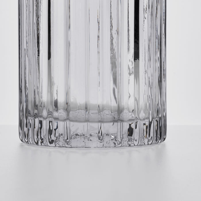 Clear glass decanter with vertical ribbed texture and rounded base, shown from above against white background.