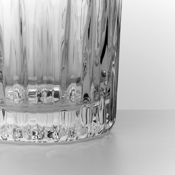 Close-up of two clear glass double old-fashioned glasses with vertical ribbed texture pattern.