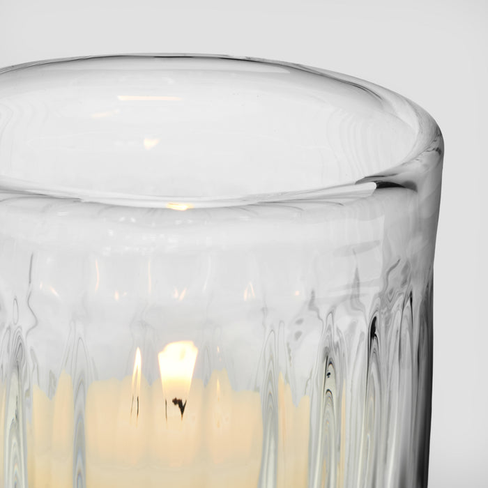 Clear glass tumbler with textured ridged pattern containing pale yellow liquid.