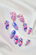 Mystic Daisy by Jess Miller press-on nails with pink floral and wavy blue/pink designs on a satin background.