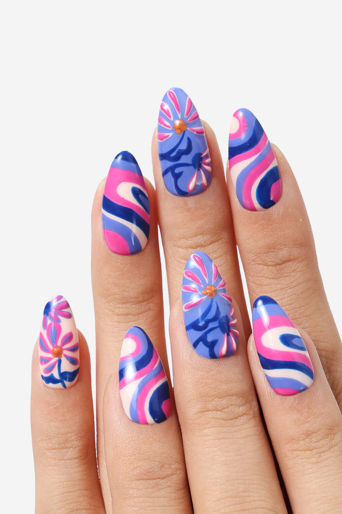 Mystic Daisy press-on nails feature a groovy floral design with wavy patterns in pink, blue, and white.